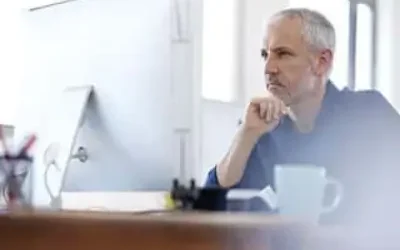 A man sitting at a desk, engrossed in what's on the computer screen.