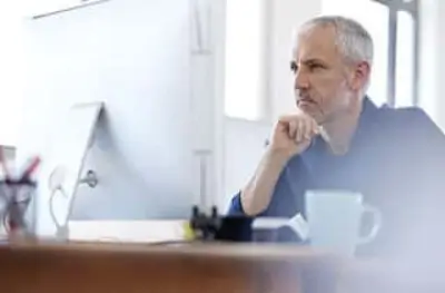 A man sitting at a desk, engrossed in what's on the computer screen.