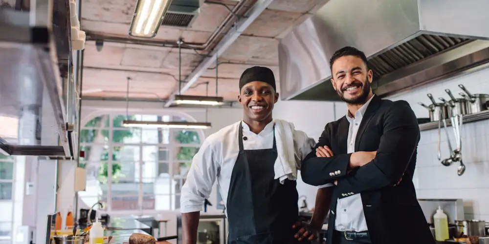 A chef and the restaurant owner standing together in a kitchen